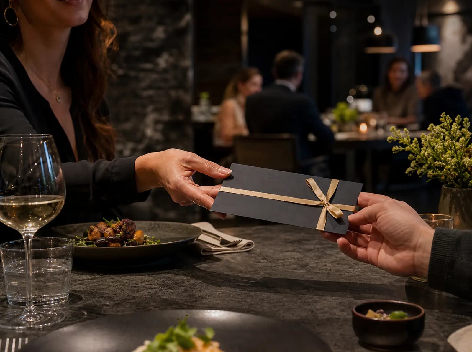 Ein hochwertig verpackter Restaurantgutschein wird am gedeckten Tisch überreicht